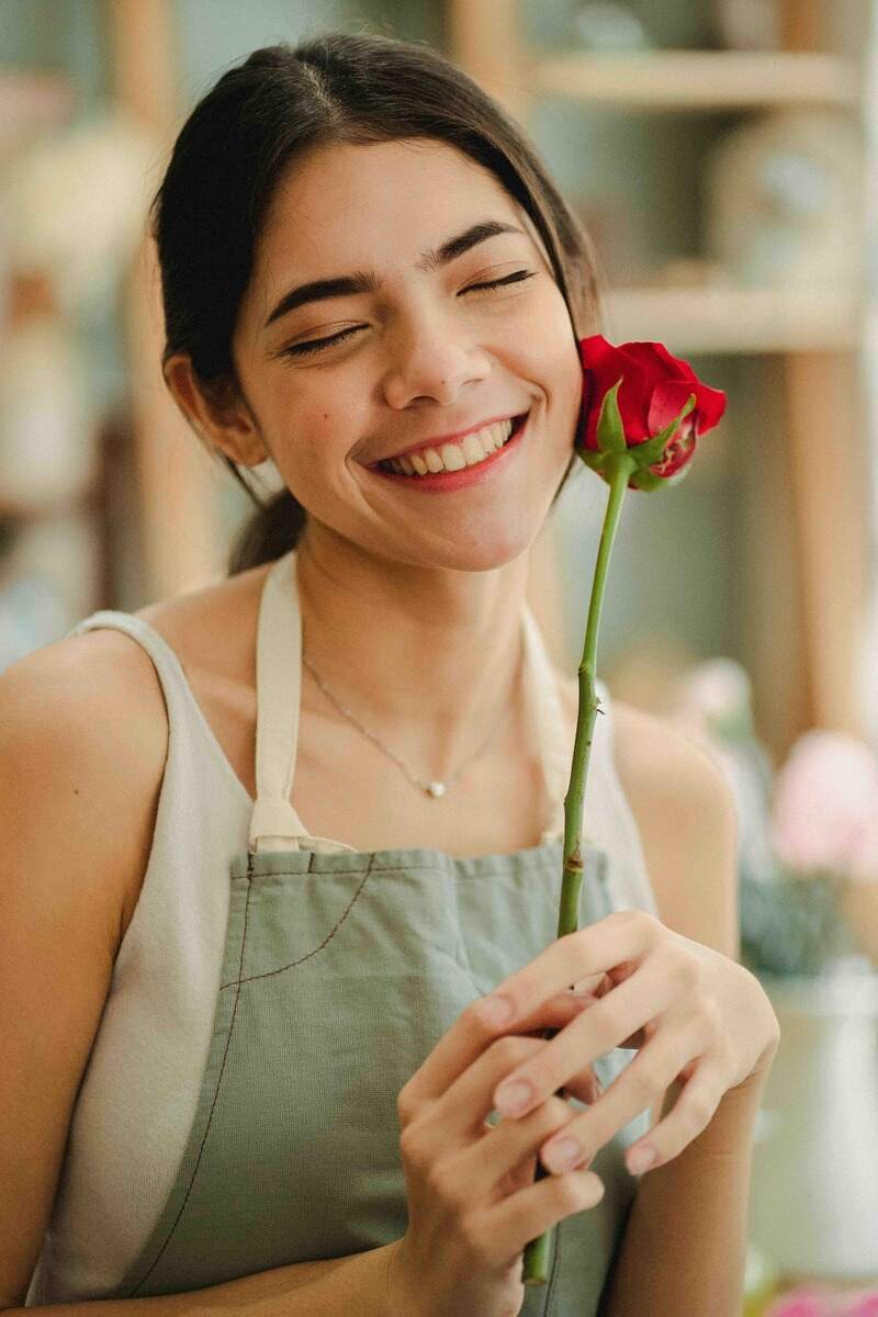 ragazza che sorride con rosa rossa in mano
